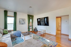 Ein geräumiges Wohnzimmer mit einer Couch, einem Couchtisch und einem an der Wand befestigten Fernseher.