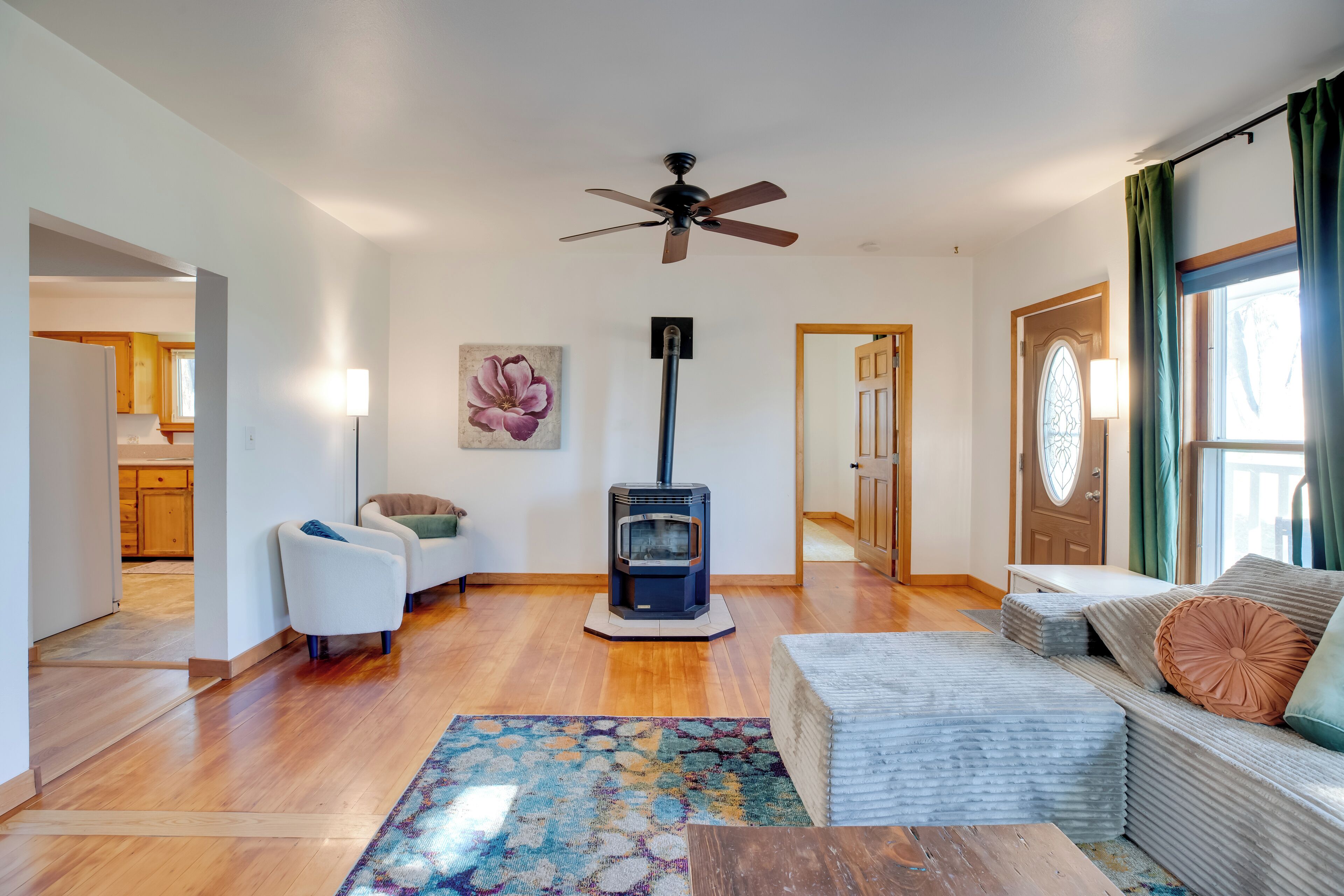 A living room with a sofa, a coffee table, a rug, a fireplace, and a ceiling fan.