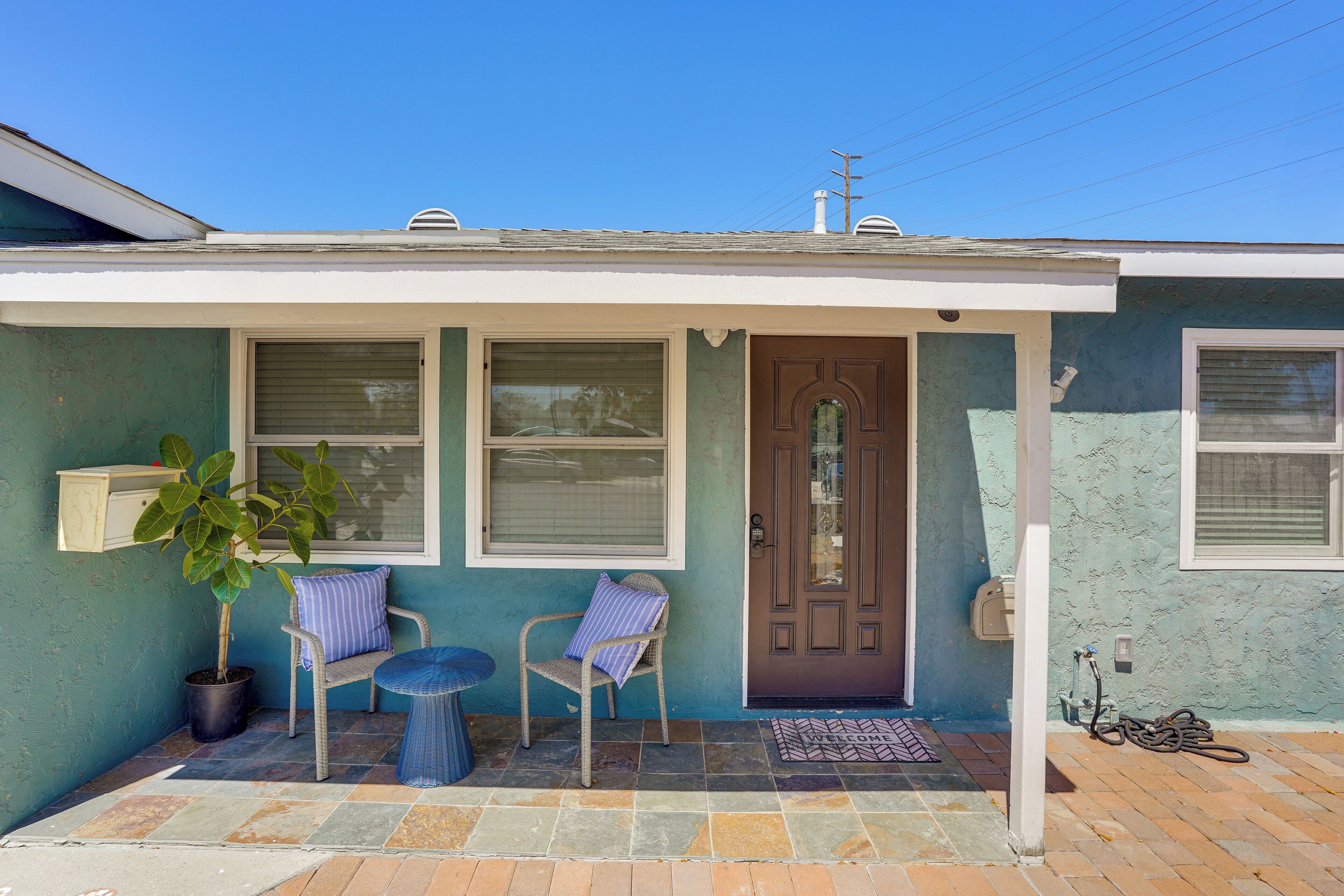 A house with a porch, two chairs, a potted plant, and a door.