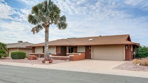 Ein Bungalow mit Garage, Veranda und einer Palme.