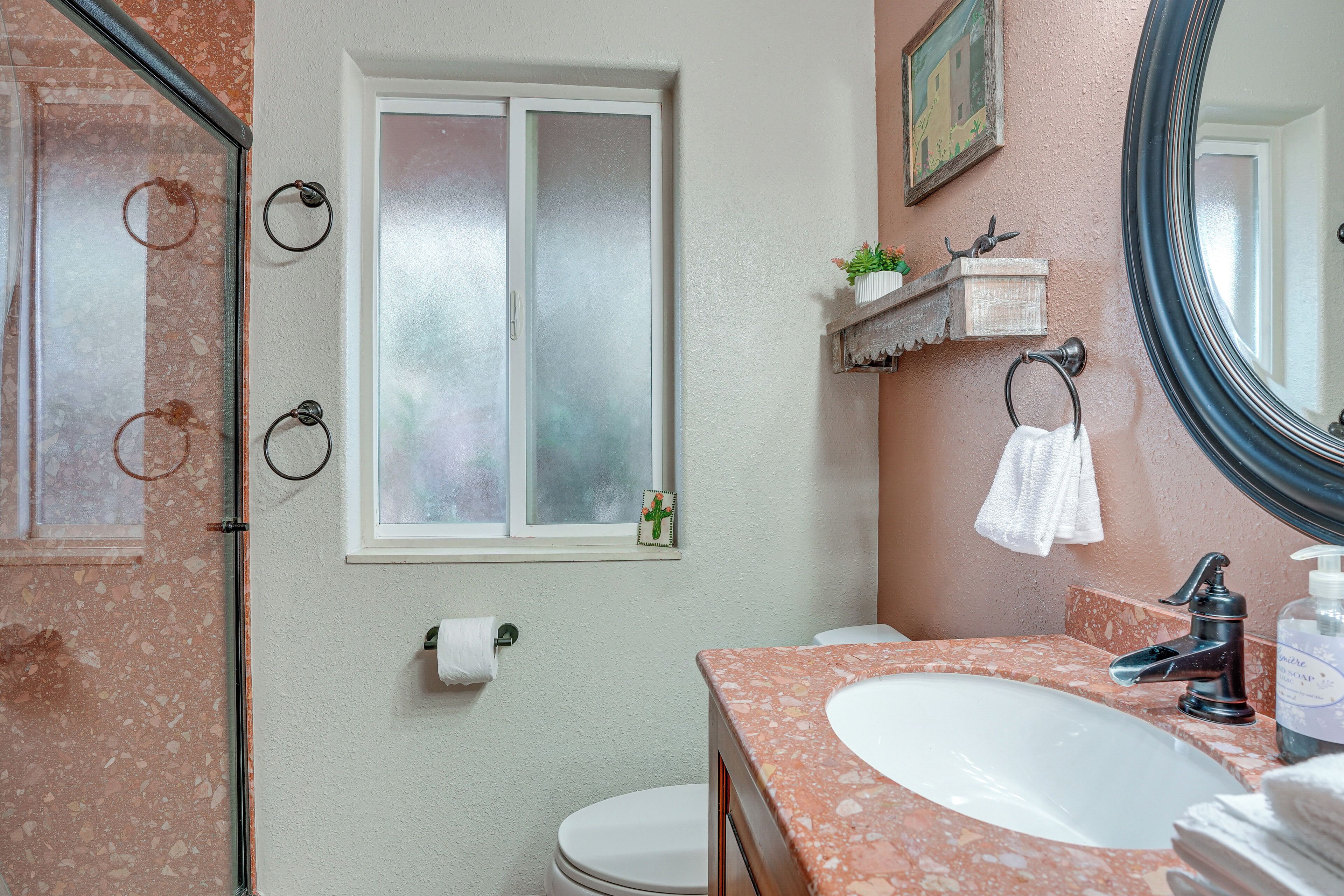Un baño con lavamanos de mármol, inodoro, ducha y espejo.