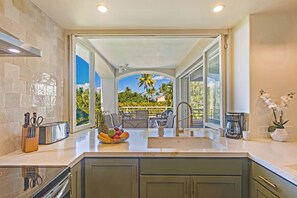 A modern kitchen with a large island, a built-in oven, and a view of a patio with outdoor furniture.