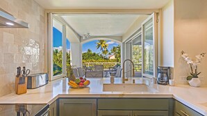 Una cocina moderna con una isla grande, horno empotrado y vistas a un patio con mobiliario exterior.