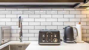 A kitchen with a toaster, kettle, and modern faucet. - Relaxing 1BR CBD Retreat with Rooftop pool & Gym (Auckland)