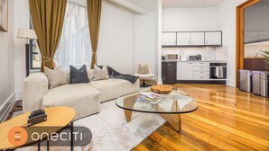 A modern living room with a sofa, a glass coffee table, and a dining area with a kitchen in the background. - Relaxing 1BR CBD Retreat with Rooftop pool & Gym (Auckland)