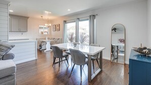 Une cuisine moderne avec des meubles blancs, une table à manger avec quatre chaises et une grande fenêtre agrémentée de rideaux.
