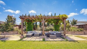 Un espace extérieur aménagé, abrité et doté d’une pergola, de sièges confortables et d’un chemin en pierre.