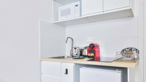 Une petite cuisine équipée d’un four à micro-ondes, d’une bouilloire, d’une machine à café et d’un petit réfrigérateur.