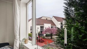 Un balcone con vista su una zona residenziale, tra cui case e un albero in fiore di colore rosa.