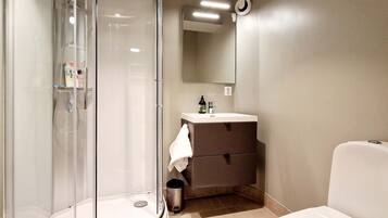 A modern bathroom with a glass-enclosed shower, a white sink, and a toilet.