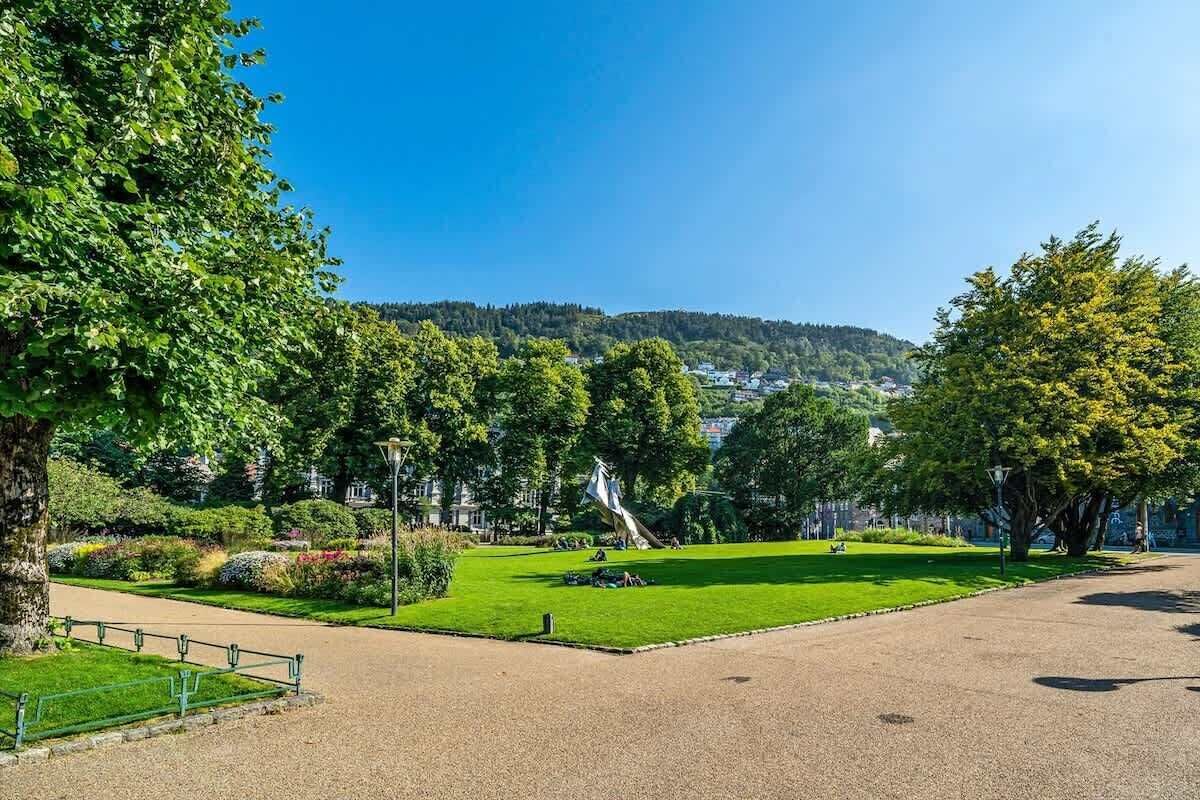 A park with a statue, green lawns, and trees.