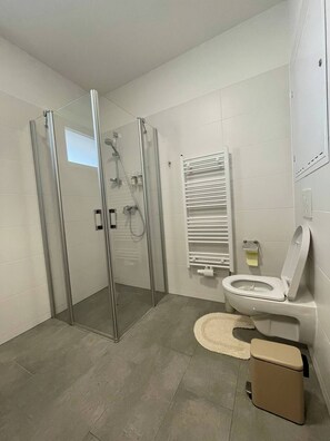 A modern bathroom with a glass-enclosed shower, a toilet, and a bidet. - Luxurious Modern Apartment in Raaba, Graz’s Business District (Raaba)