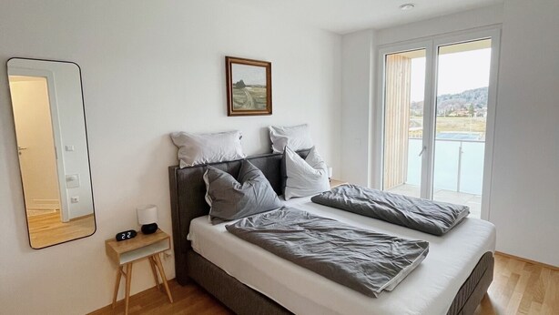Une chambre à coucher moderne avec un grand lit, une table de chevet, un miroir et un tableau au mur.