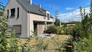 A modern two-story house with a sloped roof, large windows, and a visible chimney.