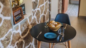 Une table à manger avec un saladier rempli de pâtisseries, une assiette bleue et des couverts.