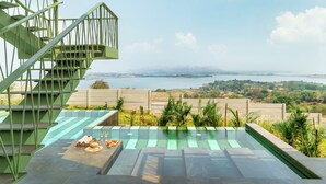 A pool area with a view of a body of water and mountains in the distance. - Verdantia (Igatpuri)