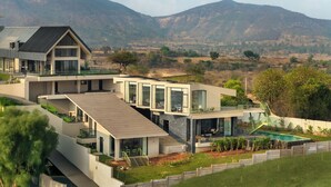 A modern house with multiple levels, large windows, and a swimming pool. - Verdantia (Igatpuri)