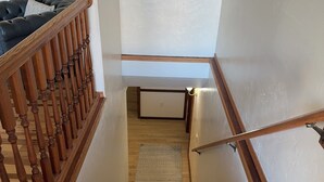A wooden staircase with a carpeted landing and a dark leather couch in the background. - Lovely 3-bedroom condo with AC in De Pere, WI. 10 min drive from Lambeau field. (De Pere)