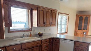 A kitchen with wooden cabinets, a dishwasher, and a window with blinds. - Lovely 3-bedroom condo with AC in De Pere, WI. 10 min drive from Lambeau field. (De Pere)