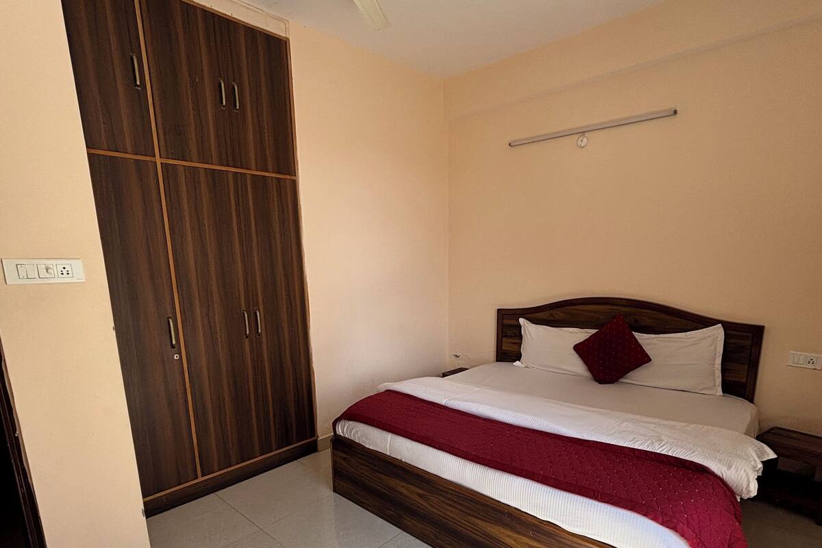 A bedroom with a bed, a wardrobe, a ceiling fan, and a light fixture.