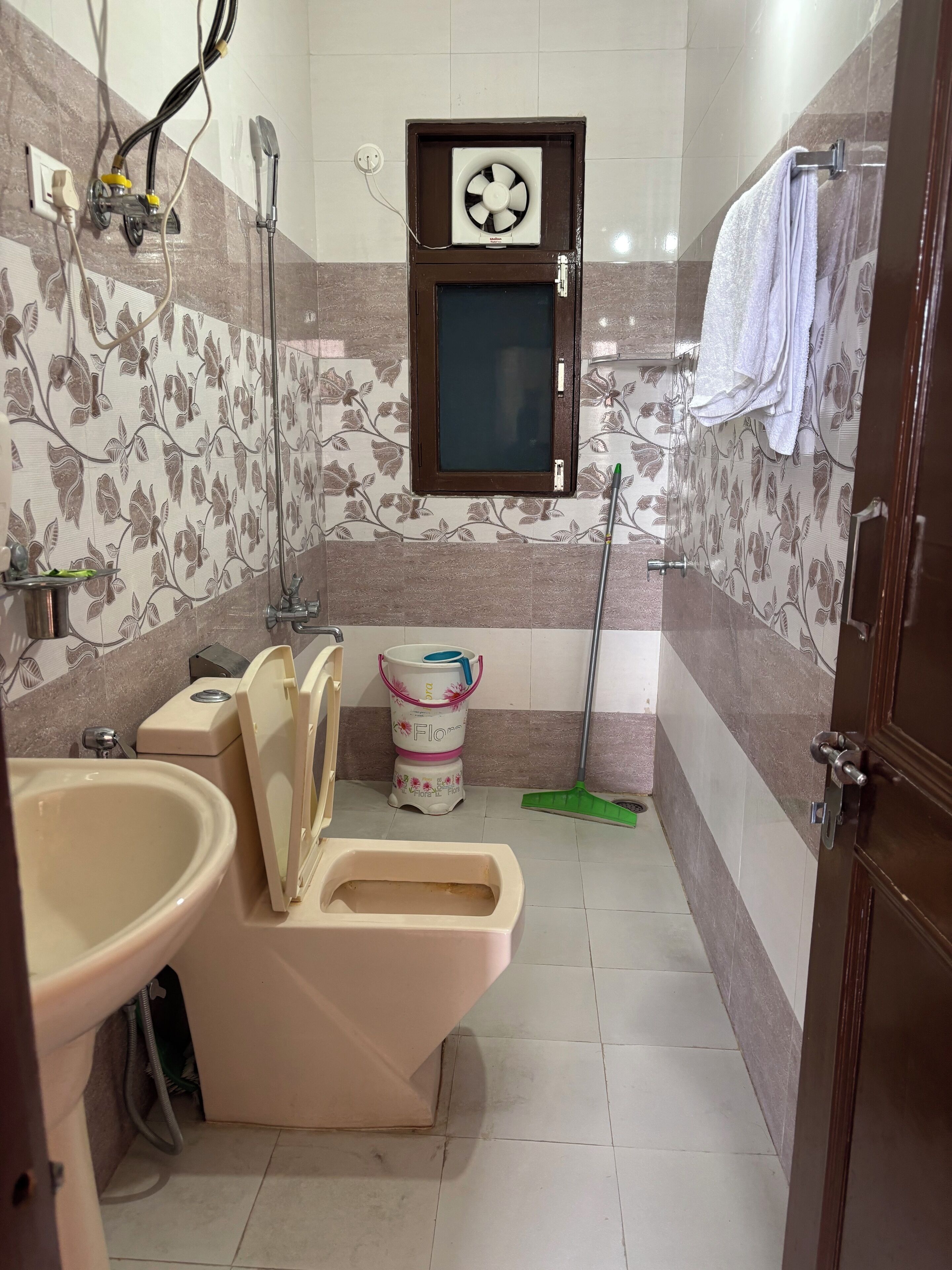 Une salle de bain équipée de toilettes, d’un bidet, d’un lavabo et d’une fenêtre avec un ventilateur.