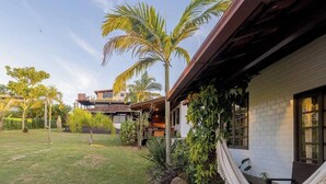A residential property with a well-maintained lawn, a two-story house, and a visible balcony. - Casas Valley Design - Praia do Rosa - SC (Imbituba)