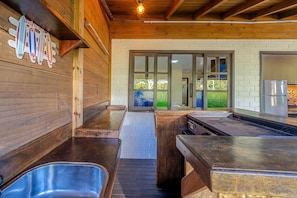A kitchen area with wooden walls, a stainless steel sink, and a refrigerator.