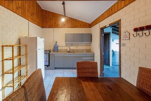 A kitchen with a wooden ceiling, white brick walls, a refrigerator, and a sink. - Casas Valley Design - Praia do Rosa - SC (Imbituba)