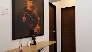 A hallway with a framed portrait, a bench, and a door. - Studio Apartment ( Kitchen ) (Mumbai)
