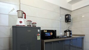 A modern kitchen with a refrigerator, microwave, kettle, and a coffee maker on the countertop. - Studio Apartment ( Kitchen ) (Mumbai)
