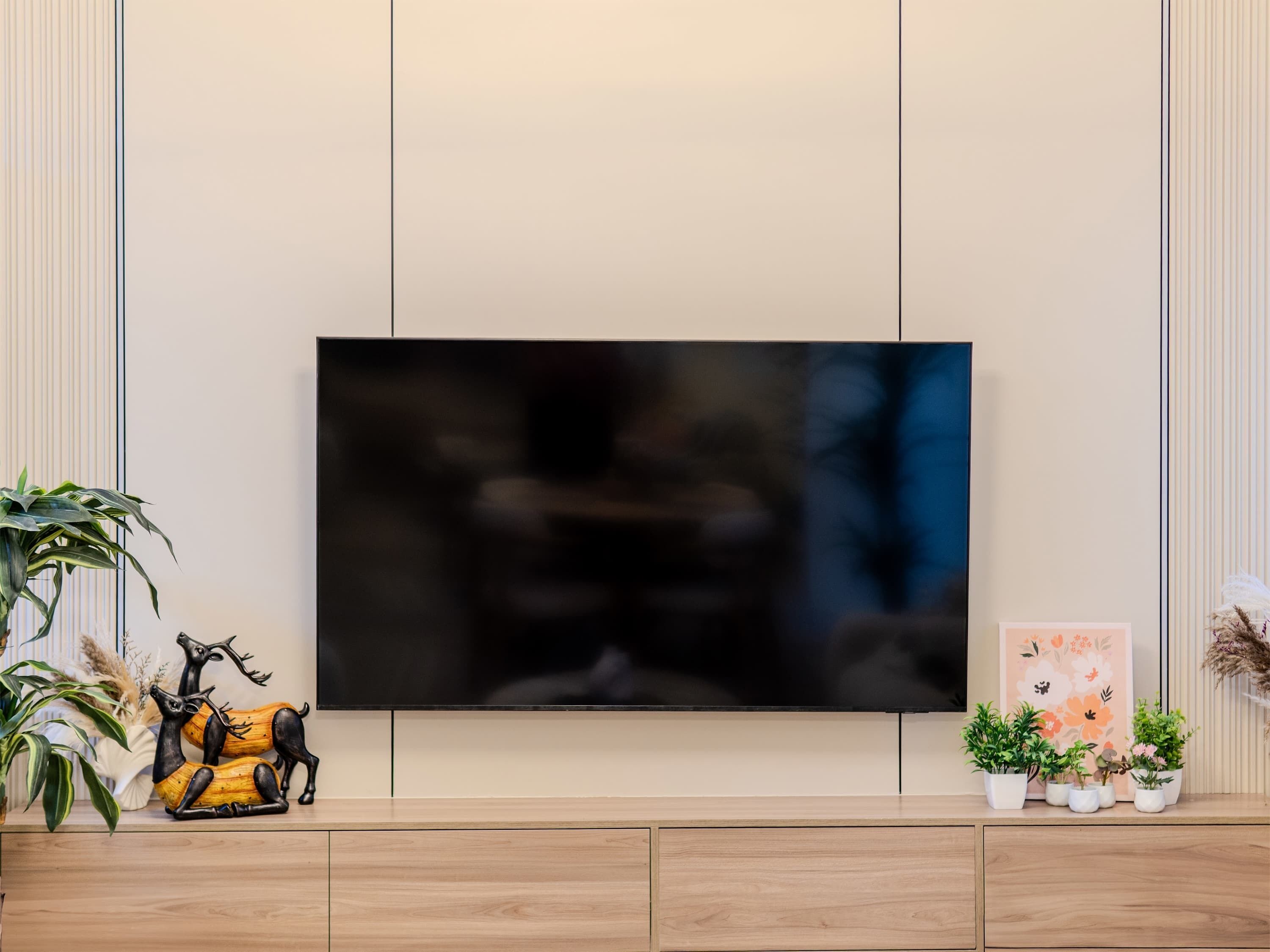 Un téléviseur à écran plat fixé au mur, avec un meuble en bois placé en dessous.