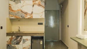 A modern kitchen with marble countertops, a built-in sink, and a small refrigerator.