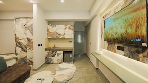 A modern living room with a marble-patterned sofa, a small coffee table, and a TV mounted on the wall displaying a nature scene.