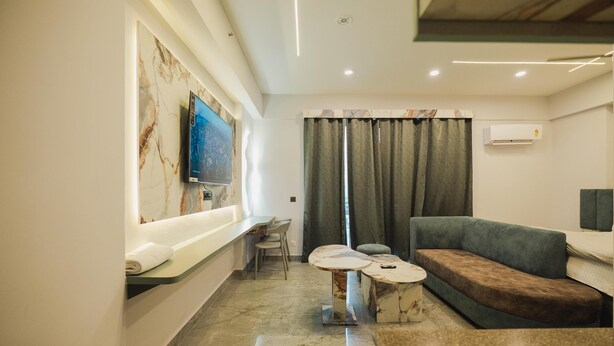 A modern living room with a marble floor, a sofa, a coffee table, a TV mounted on the wall, and a window with curtains.