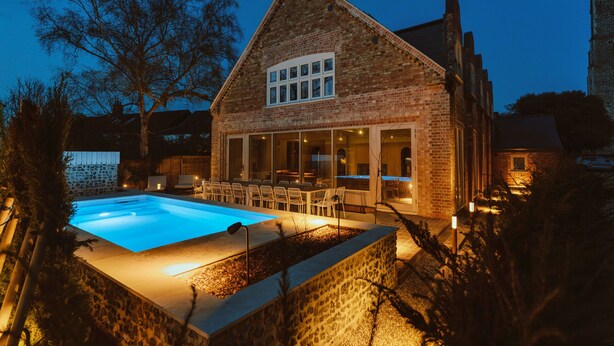 Ett hus byggt av tegel med en swimmingpool, en uteplats och en mur av sten.
