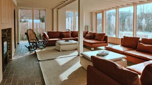 Ett rymligt vardagsrum med ett stort fönster, en öppen spis och en bekväm sittgrupp.