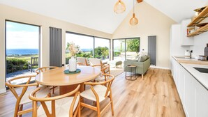 Una cocina amplia con una isla grande, un comedor con sillas de madera y vistas al exterior.