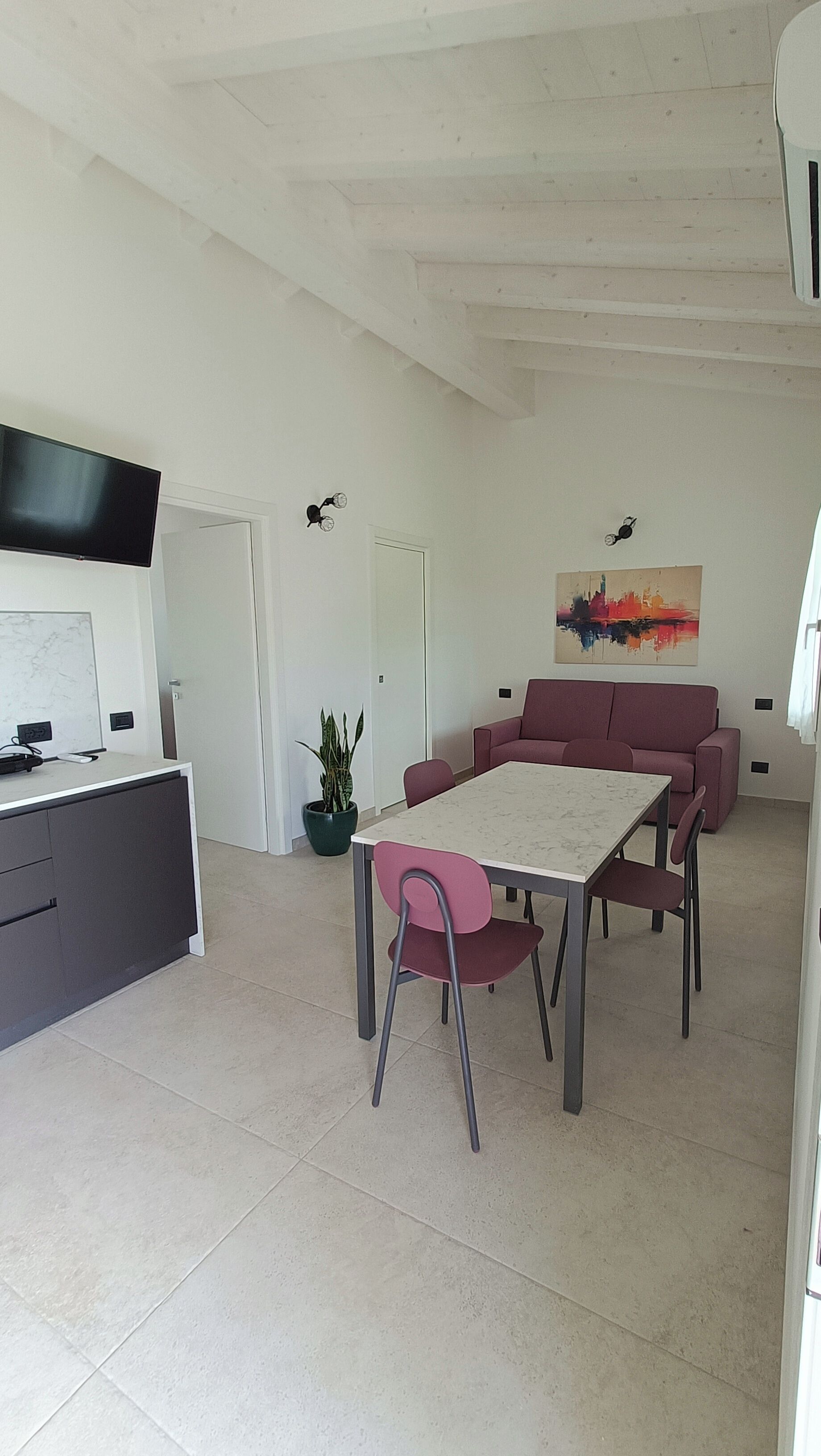 Ein modernes Wohnzimmer mit Esstisch, Sofa und einem an der Wand befestigten Flachbildfernseher.