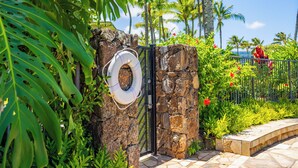 Una puerta de piedra con un flotador, rodeada de plantas tropicales y palmeras.