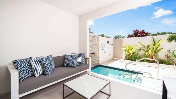 Un espace piscine intérieur moderne, doté d’un canapé et d’une table basse en verre.