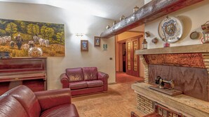 Ein Wohnzimmer mit Kamin, Ledersofa und einem Gemälde von Kühen.
