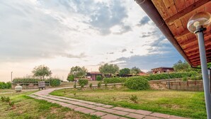 Ein Weg führt durch eine angelegte Grünfläche, im Hintergrund ist ein Gebäude zu sehen.