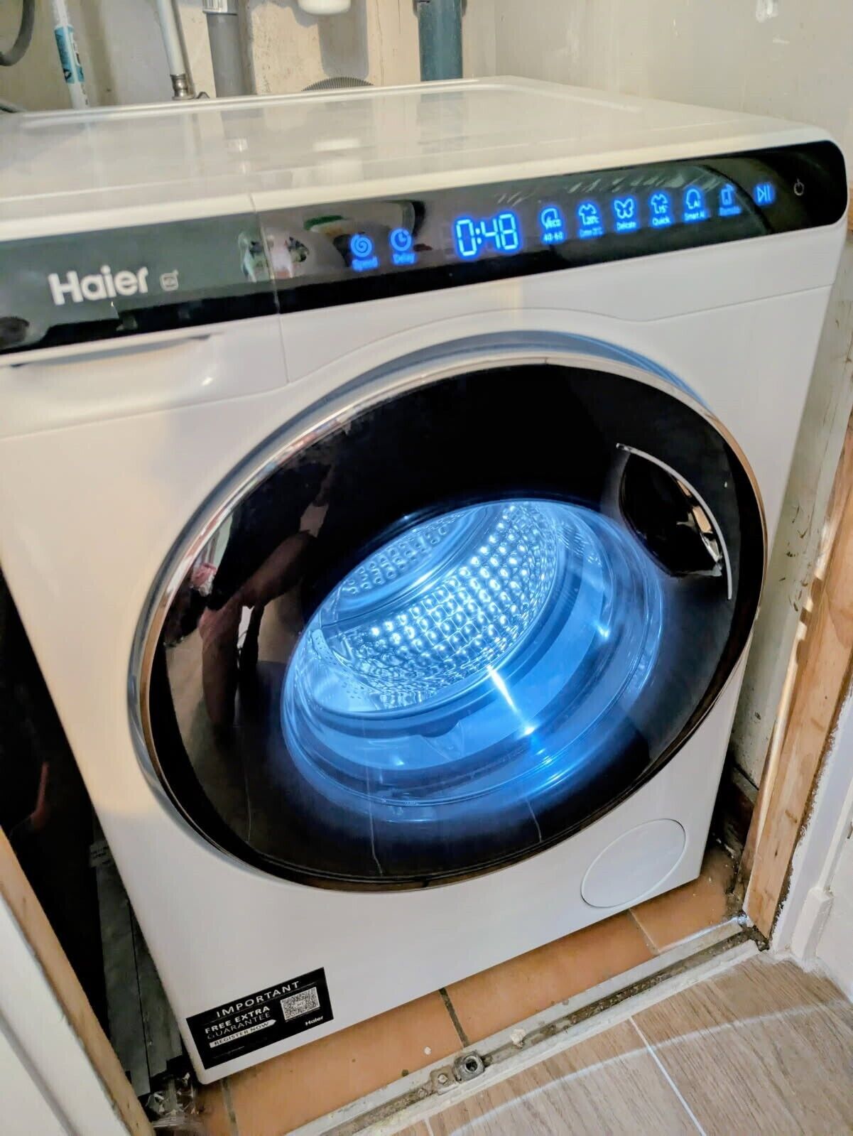 En tvättmaskin från Haier med frontmatning, digital display, en QR-kod och en etikett med texten ”VIKTIGT”.