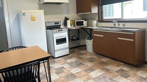 Eine kleine Küche mit Kühlschrank, Herd, Mikrowelle und Holzschränken.