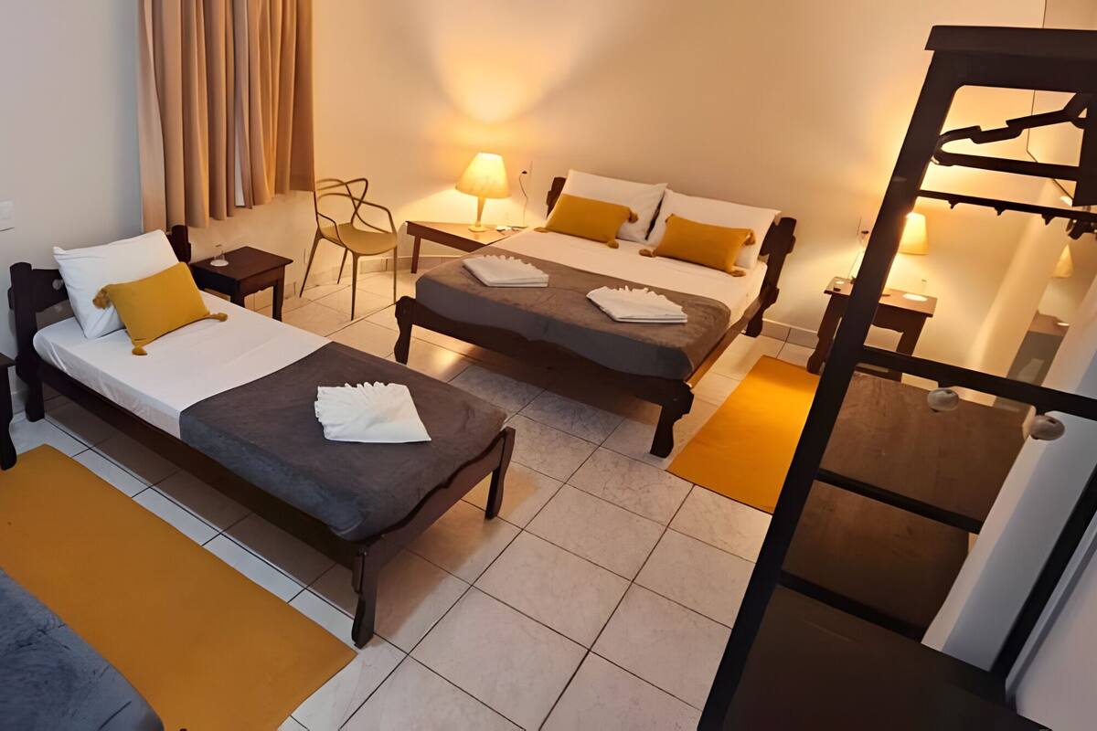 A hotel room with two single beds, a sofa bed, a desk, and a chair.