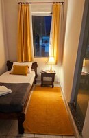 A hotel room with a bed, a nightstand, a lamp, and a window with curtains.