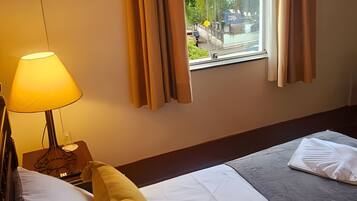 Una habitación de hotel con cama, lámpara y vistas al exterior.