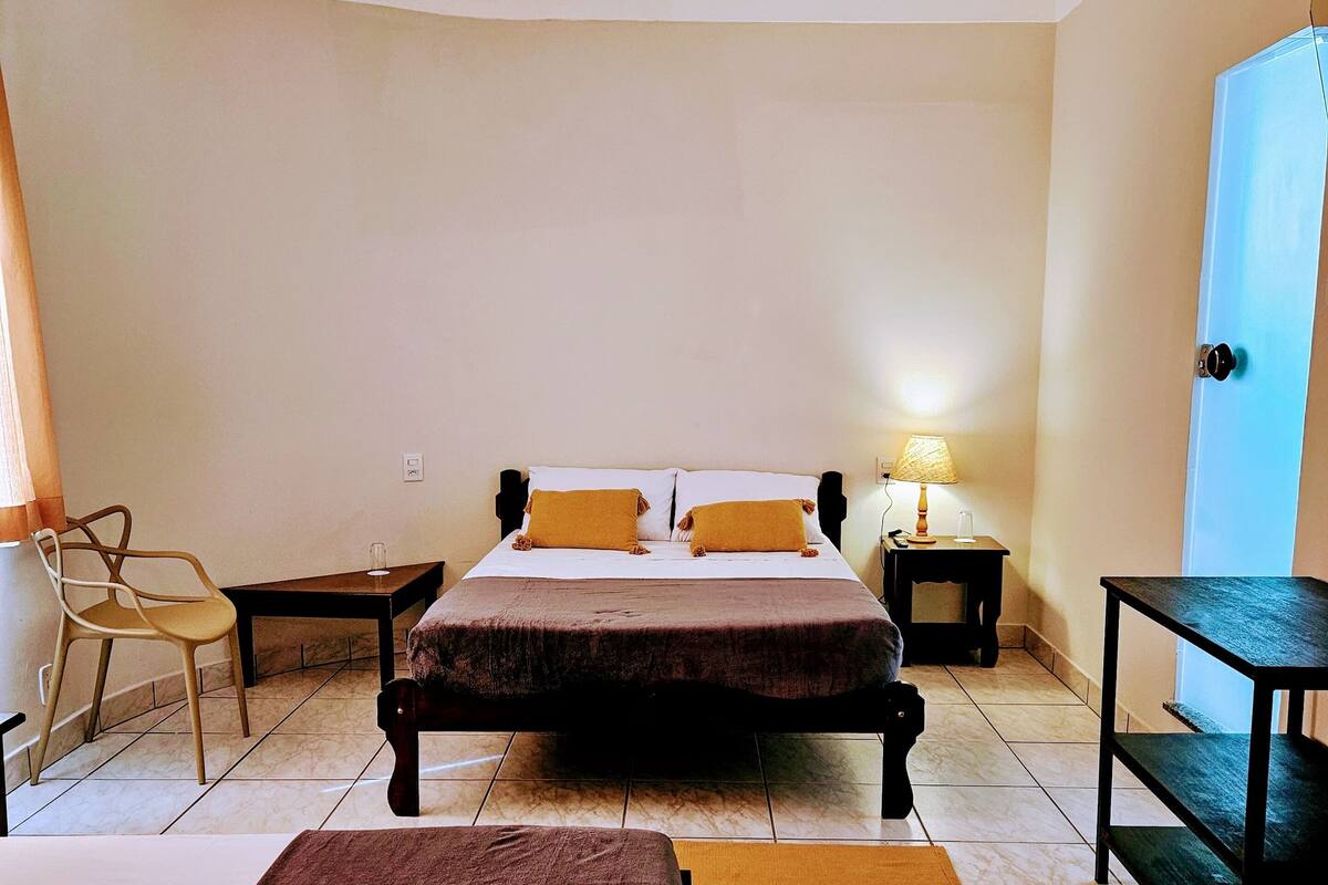A bedroom with two beds, a chair, a table, and a lamp.