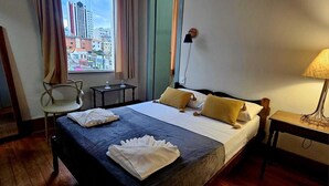 A hotel room with a bed, a chair, a table, and a lamp. - Hotel Barbacena (Barbacena)