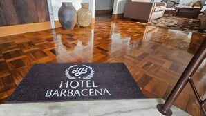A hotel entrance with a polished wooden floor and a doormat that reads "HYB HOTEL BARBACENA". - Hotel Barbacena (Barbacena)
